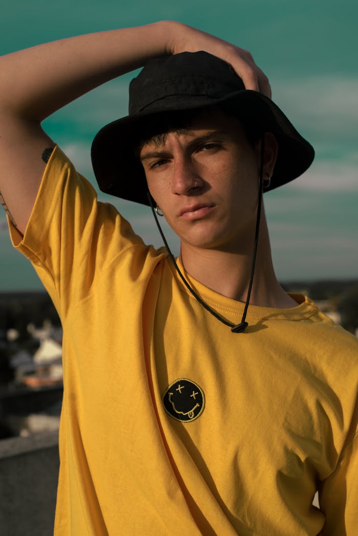 Portrait of a fashionable young man wearing a yellow t-shirt and hat, posing confidently.